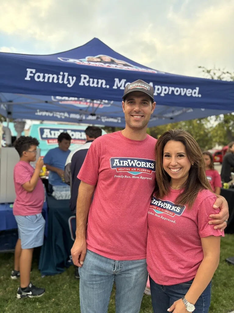 Stephanie and Kevin Allen in AirWorks shirts under the Family Run, Mom Approved canopy at a summer concert.