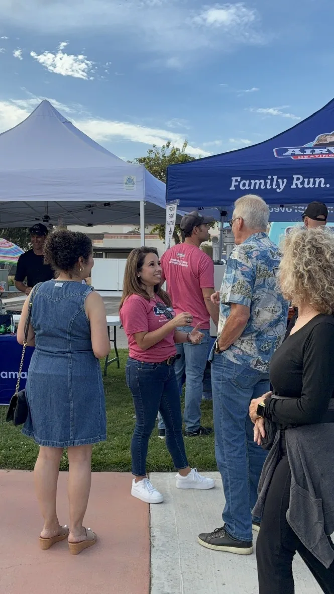 Stephanie Allen talking with residents beside the AirWorks booth at a Pleasant Valley summer concert.